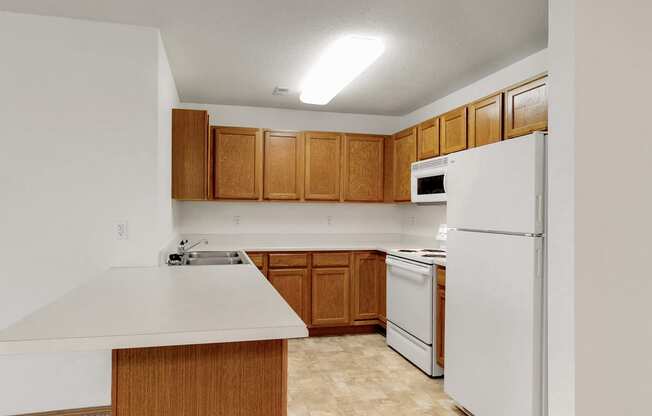 an empty kitchen with white appliances and wooden cabinets