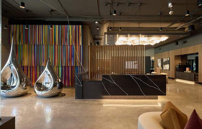 A reception area with a striped wall and two large silver vases.