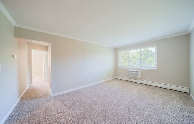 Living room with window and carpeting leading to hallway