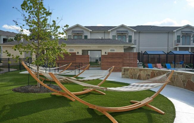 a backyard with two hammocks and a tree