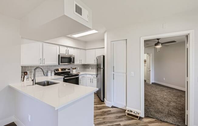 a kitchen with white cabinets and stainless steel appliances