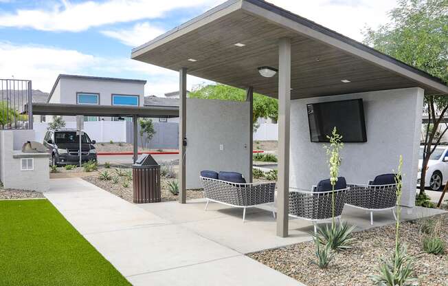 a patio with chairs and a television on the side of a house