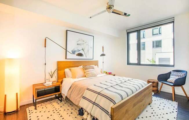 A bedroom with a bed, a chair, and a painting on the wall.