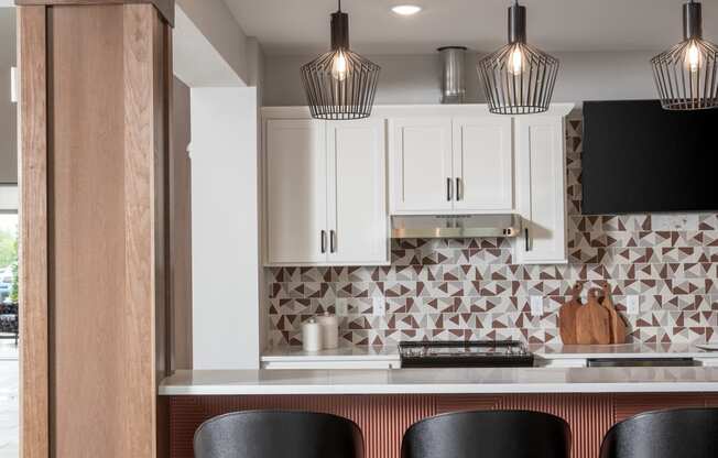 a kitchen with three black stools in front of a bar with black chairs at The Edison at Maple Grove, Maple Grove