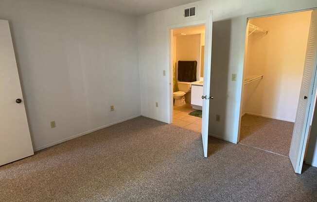 Carpeted Bedroom with white walls and with folding closet door, and view of bathroom and closet