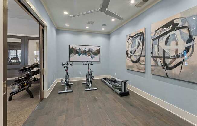 A room with a wooden floor and a wall with two paintings on it.