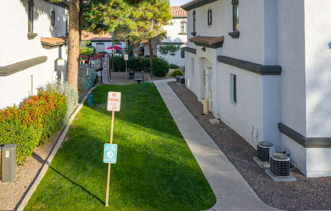 A sign on a post in a grassy area between two buildings.