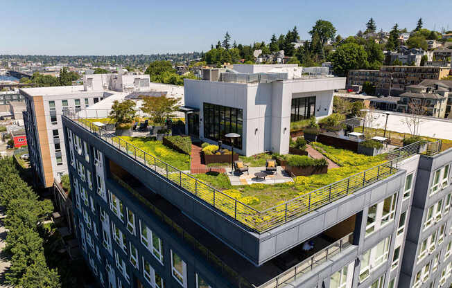A modern building with a green roof is surrounded by other buildings.