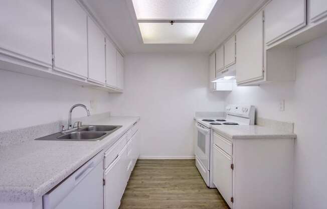 an empty kitchen with white cabinets and appliances and a sink