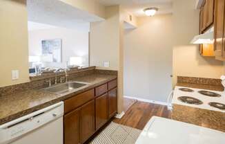 A kitchen with a white dishwasher and brown cabinets.
