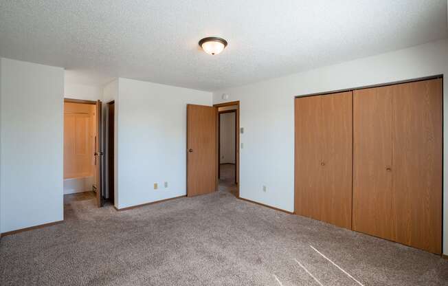 a bedroom of an empty apartment with carpeting and wood doors. Fargo, ND Westview Towers Apartments