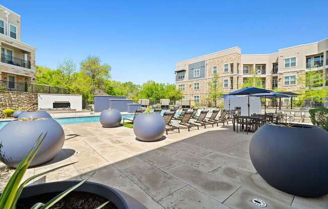 A pool area with a stone wall and a building in the background.