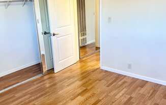 a bedroom with hardwood floors and white walls