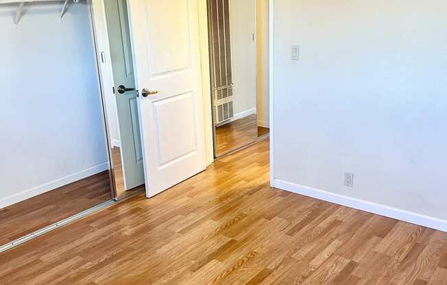 a bedroom with hardwood floors and white walls