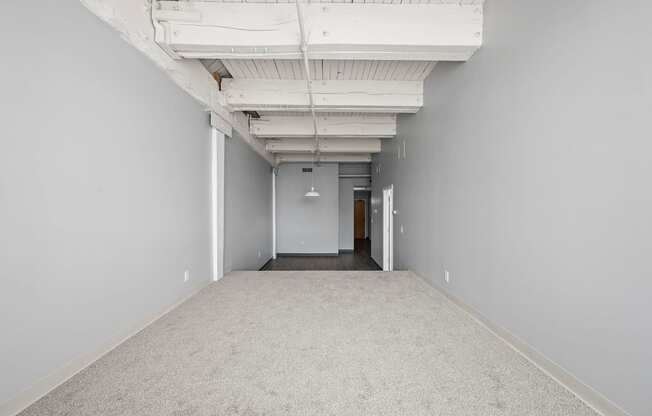 A long, empty hallway with a carpeted floor and white walls.