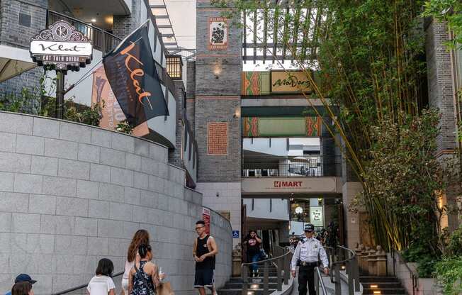 a man in a police uniform stands at the bottom of a flight of stairs with people walking