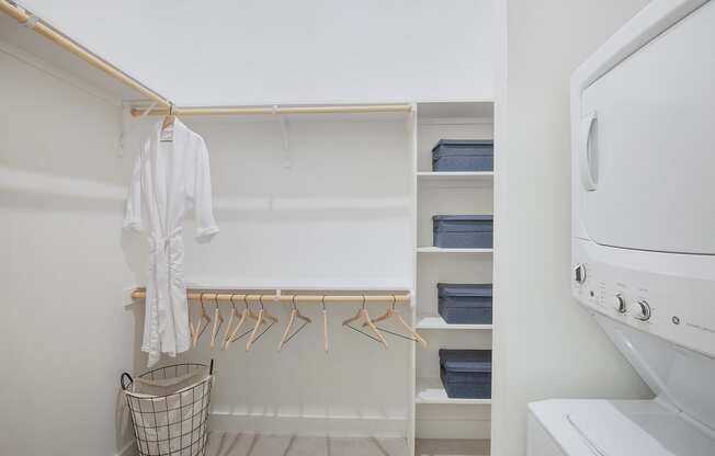 a laundry room with a washer and dryer and a closet with hangers