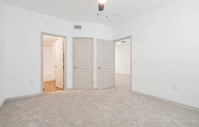 an empty living room with two doors and a carpeted floor