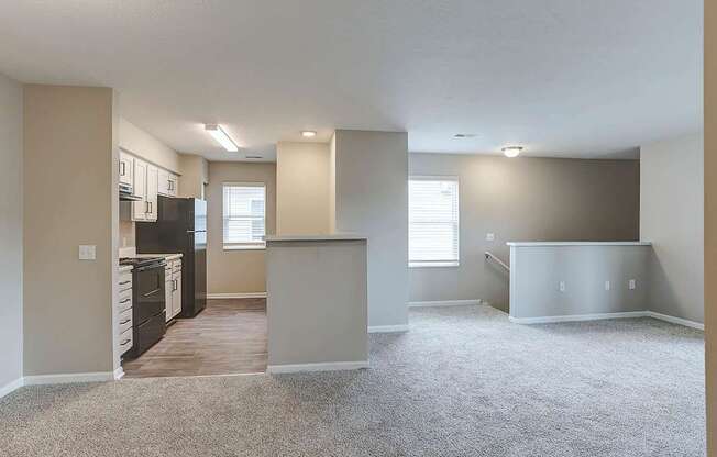 A spacious living room with a kitchen area in the background.