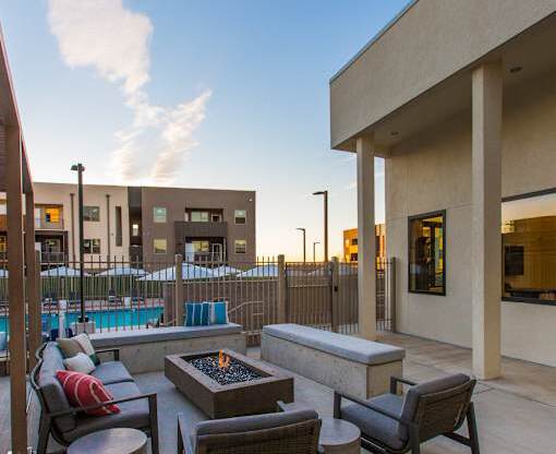 A patio with a fire pit and chairs.