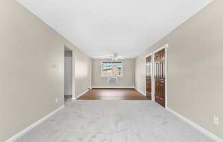 a spacious living room with a white carpet and a door to a bedroom