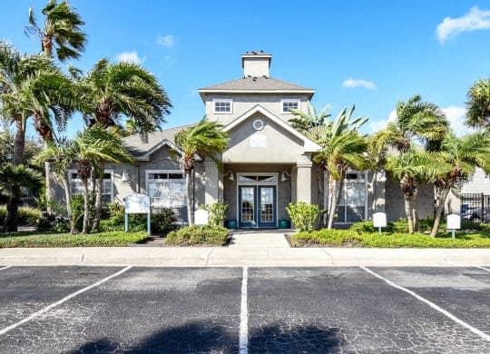 a house with palm trees in front of a parking lot