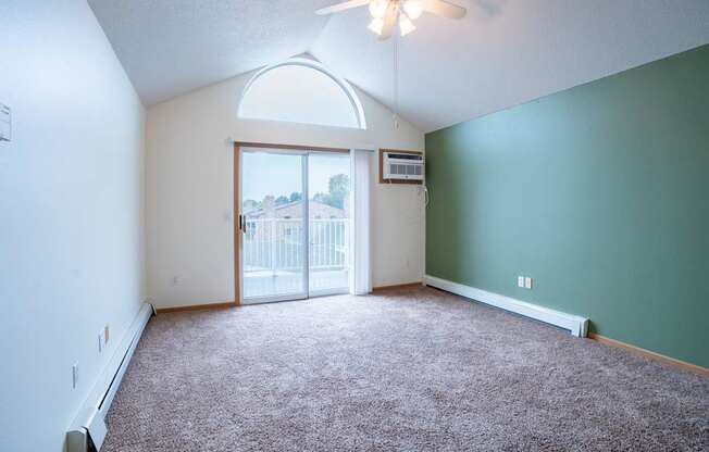 A room with a carpeted floor and a ceiling fan. Fargo, ND Summit Point Apartments