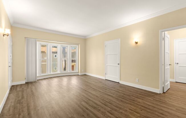 the living room of an empty home with wood floors and doors