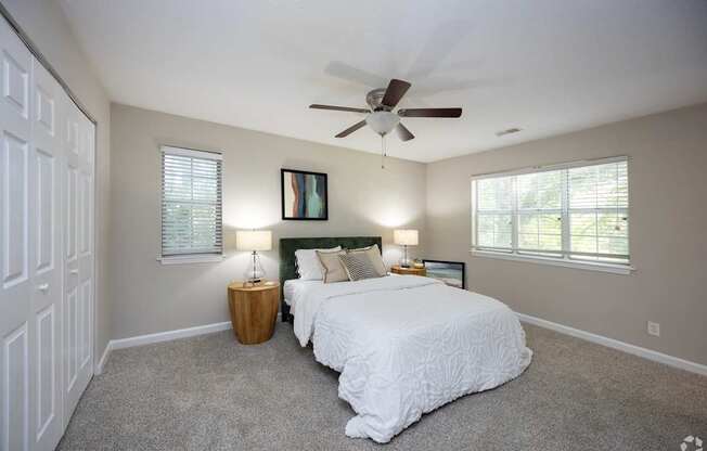 A bedroom with a white bed and a ceiling fan.