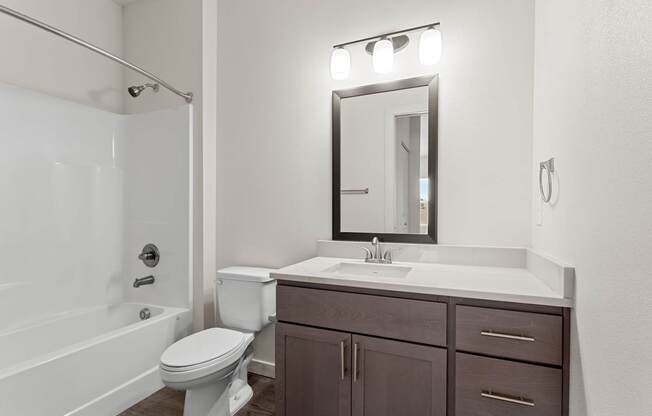 A white bathroom with a toilet, sink, and a mirror.