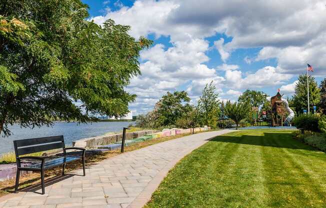 A park with a bench and a pathway leading to a body of water.