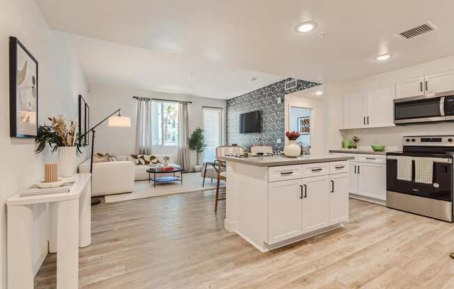 a kitchen and living room with white walls and wood flooring