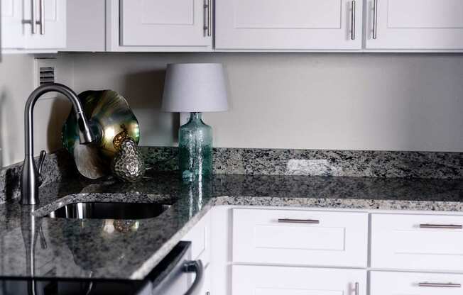 a white kitchen with marble counter tops and white cabinets at Hampton Plaza Apartments in Towson, MD 21286