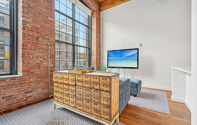 a living room with a large window and a dresser with a tv on it