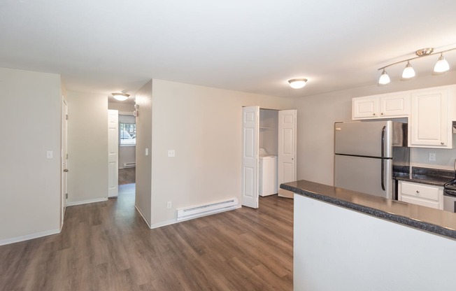 a living room with hardwood floors and a kitchen with stainless steel appliances