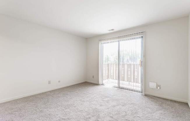 A room with a carpeted floor and a sliding glass door
