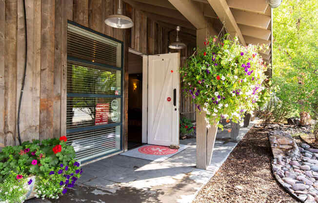 the front door of a wooden building with flowers in front of it at Mullan Reserve Apartments, Montana