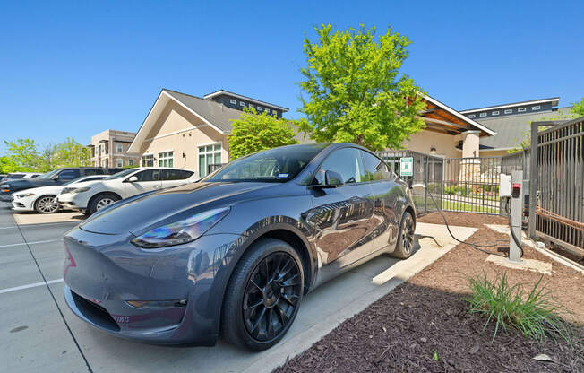 A grey Tesla Model 3 is parked in a parking lot.
