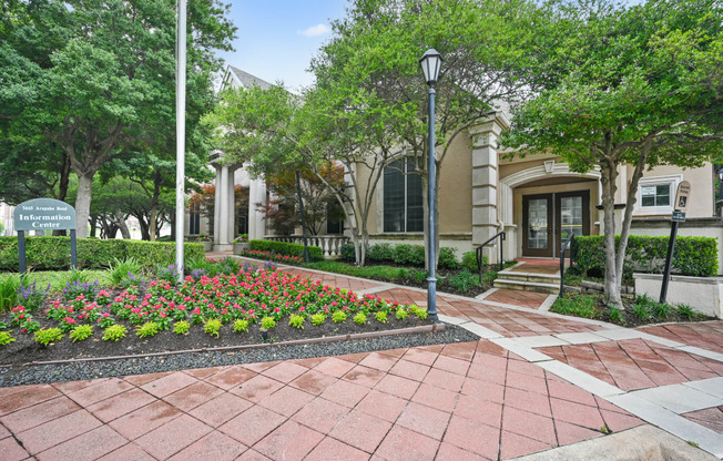 a courtyard with flowers and trees in front of a building