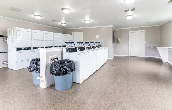an empty room with white cabinets and trash cans in it