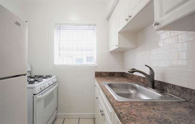 A kitchen with a white stove and a white refrigerator.