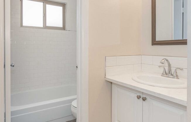 a bathroom with white cabinets and a sink and a toilet