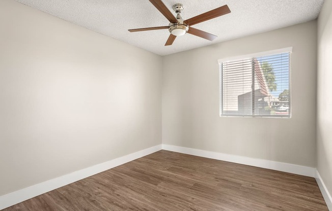 an empty room with a ceiling fan and a window