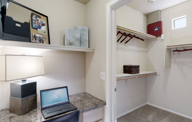 a laptop on a desk in a room with a walk in closet