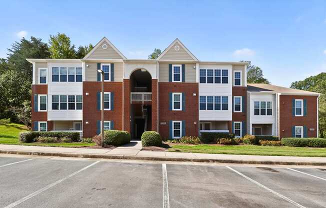 A large apartment complex with a parking lot in front.