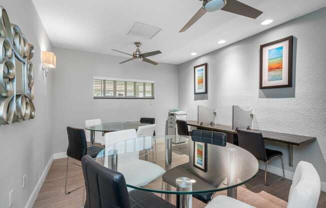 a dining room with a glass table and chairs and a ceiling fan