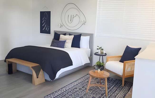 A bedroom with a bed, a bench, and a rug.