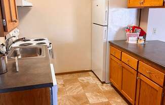 A kitchen with a white refrigerator and wooden cabinets.