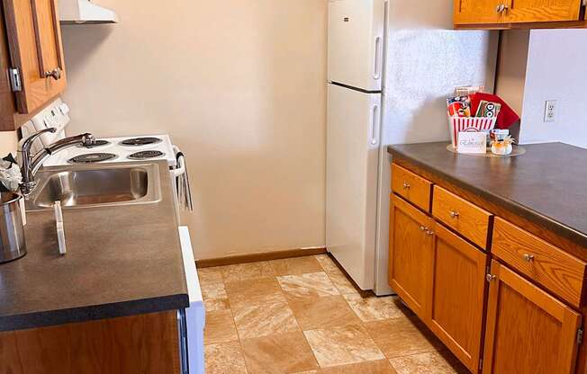 A kitchen with a white refrigerator and wooden cabinets.
