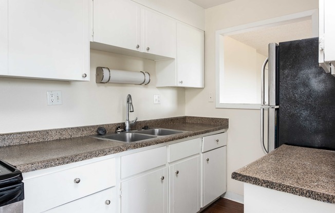 a kitchen with white cabinets and a sink and a refrigerator